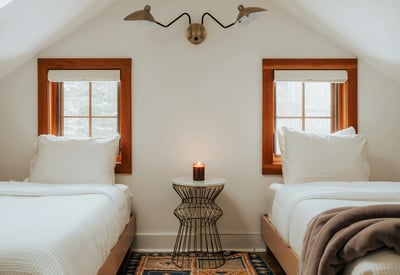 Cozy twin bedroom featuring natural light, unique decor, and a warm ambiance for restful stays.