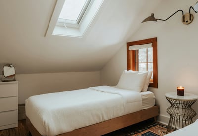 Bright, airy bedroom features a skylight, cozy bedding, and modern decor for a perfect retreat.