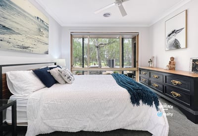 Spacious bedroom featuring large windows, natural light, and a view of lush outdoor greenery.