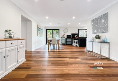 Spacious open-concept living area with warm wooden floors and abundant natural light, ideal for entertaining.