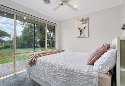 Bright and airy bedroom with large windows offering stunning views of the lush backyard.