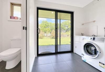 Bright laundry room featuring a washing machine, ample storage, and direct access to the outdoor space.