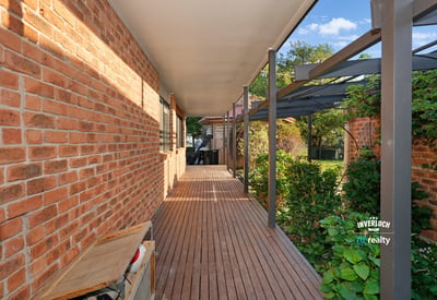 Inviting walkway lined with brick and greenery, leading to a secluded outdoor living space.