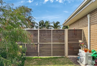 This property features a private outdoor space bordered by modern fencing and vibrant landscaping.
