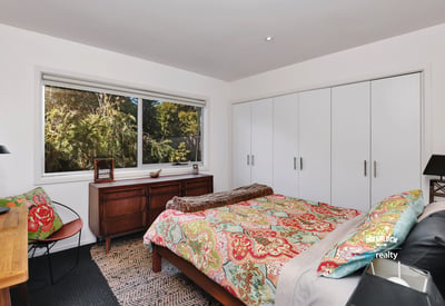Bright bedroom featuring ample storage, a comfortable bed, and large windows showcasing natural surroundings.