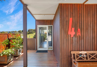 Modern entrance featuring natural wood accents, abundant greenery, and a bright, inviting atmosphere.