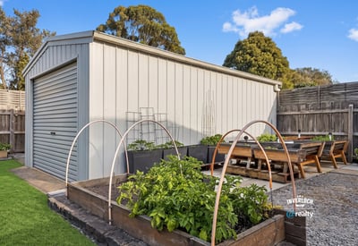 This property features a spacious backyard with a structured shed and thriving garden beds for enthusiasts.