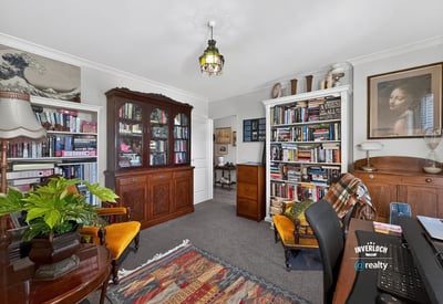 Cozy home office with built-in bookshelves, vintage furnishings, and ample natural light for productivity.