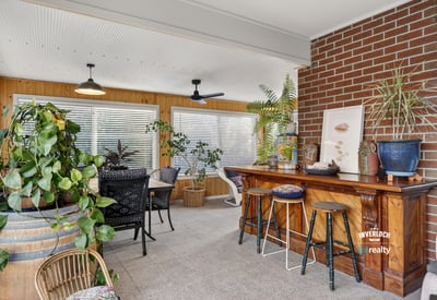 Bright sunroom featuring a cozy bar, abundant greenery, and ample natural light for relaxation and entertainment.