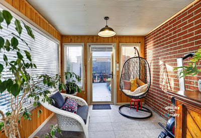 Bright sunroom featuring a cozy seating area and access to a beautifully landscaped outdoor space.