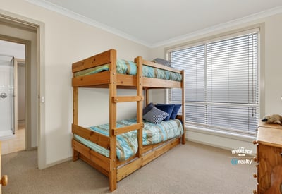 Cozy bedroom featuring a sturdy bunk bed and ample natural light from large windows.