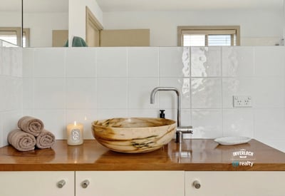 Discover a beautifully designed bathroom featuring a unique stone sink and warm, inviting accents.