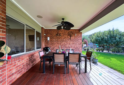 Experience outdoor dining on this spacious covered patio, featuring ample seating and picturesque landscaping.