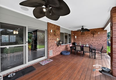 Spacious covered patio perfect for outdoor dining, featuring ceiling fans and a view of the lawn.