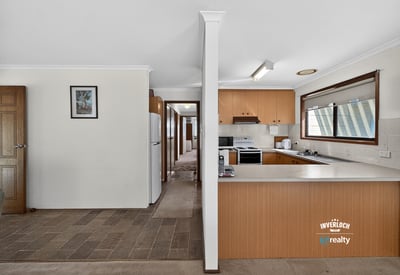Spacious kitchen with ample cabinetry leads to a light-filled, open living space perfect for gatherings.