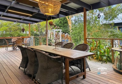 Spacious outdoor deck with ample seating, perfect for entertaining amidst lush greenery and a relaxing atmosphere.