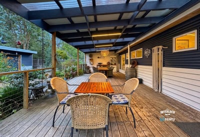 Spacious outdoor deck ideal for entertaining, featuring a cozy dining area and surrounding natural greenery.