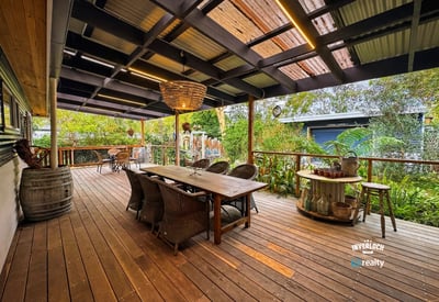 Spacious outdoor entertaining area featuring a large dining table, surrounded by lush greenery and a cozy atmosphere.
