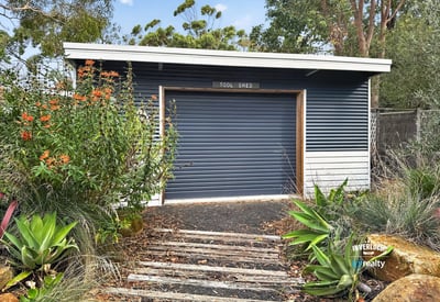 This functional tool shed offers practical storage solutions, surrounded by lush landscaping and natural beauty.