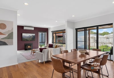 Bright and inviting open-plan living space featuring large windows and a cozy fireplace. Perfect for gatherings.