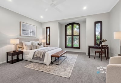 Spacious bedroom featuring large windows, plush carpet, and ample natural light for a cozy atmosphere.
