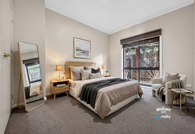 Bright and inviting bedroom featuring large windows, modern decor, and a cozy reading nook for relaxation.