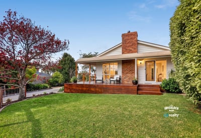 Nestled on a spacious lawn, this home features a welcoming porch and abundant outdoor greenery.