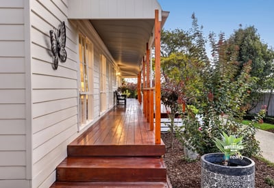 Experience the inviting atmosphere of this well-appointed home with a spacious front porch and lush surroundings.