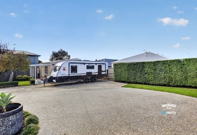 Spacious driveway perfectly accommodates an RV, surrounded by well-maintained landscaping for added privacy and convenience.