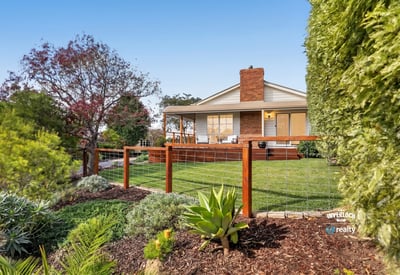 This inviting home features a spacious yard surrounded by vibrant landscaping and a welcoming front porch.