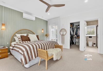 Spacious bedroom featuring unique decor, natural light, and convenient access to an organized closet and bathroom.