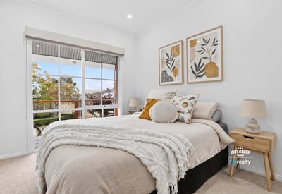 Bright and inviting bedroom featuring large windows, modern decor, and a cozy atmosphere for relaxation.