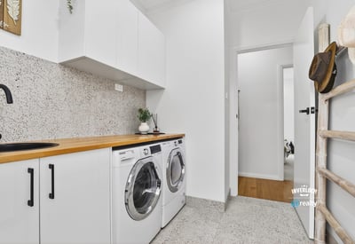 Bright laundry area featuring modern appliances, streamlined cabinetry, and a clean, functional design.