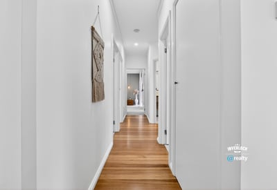 Bright and inviting hallway featuring warm wooden floors and a modern, open layout.