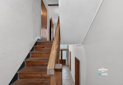 Bright and spacious staircase leading to additional living areas, featuring hardwood accents and natural light.