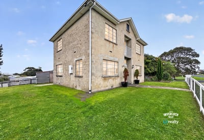 Spacious multi-level property on a generous lot, featuring large windows and expansive green yard.
