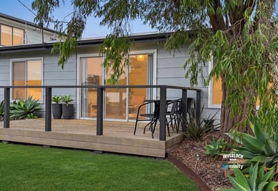 This property features a spacious deck surrounded by lush landscaping, perfect for outdoor relaxation and entertaining.