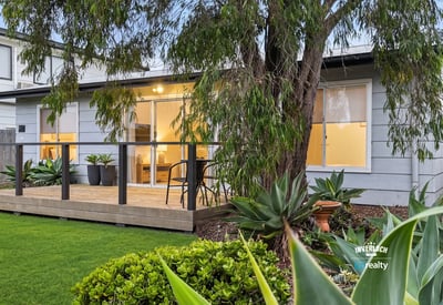 Bright and inviting home featuring a spacious deck, lush landscaping, and modern living spaces.