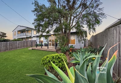 Spacious backyard with lush greenery, perfect for outdoor gatherings and relaxation near a modern home.