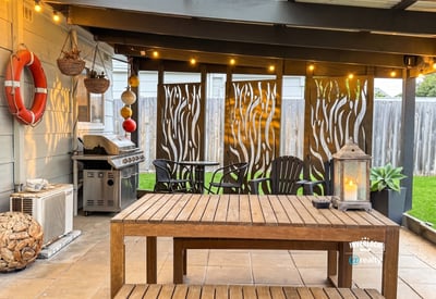 Discover an inviting outdoor space featuring a cozy dining area, grill, and decorative privacy screens.