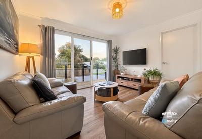 Bright living area features modern furnishings and large sliding doors that open to a scenic outdoor space.