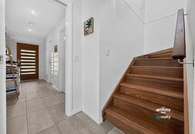 Modern entryway featuring open space, inviting natural light, and a warm wooden staircase.