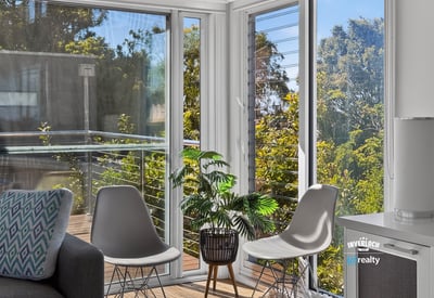 Bright and airy living space featuring large windows and a balcony with lush outdoor views.