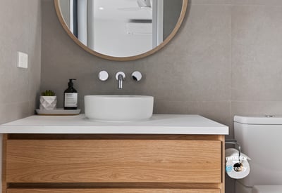 Modern bathroom featuring a sleek sink, circular mirror, and warm wooden cabinetry for practical elegance.