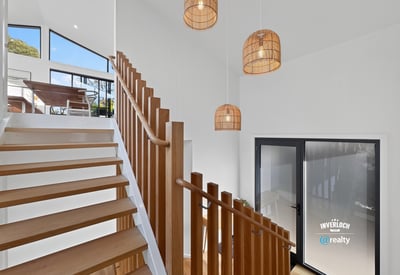 Bright and airy entryway featuring modern lighting and open staircase, seamlessly connecting indoor and outdoor spaces.