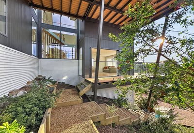 Contemporary home featuring expansive windows, a spacious deck, and beautifully landscaped outdoor areas for relaxation.