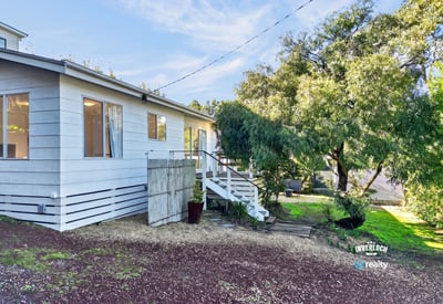 This inviting home features a spacious yard and a welcoming entrance surrounded by lush greenery.
