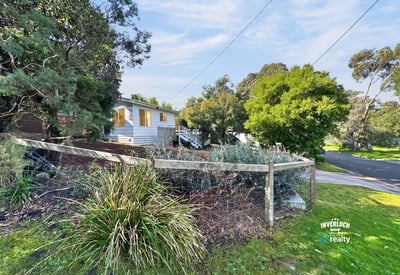 Quaint home nestled among lush greenery, featuring a spacious yard and a peaceful neighborhood setting.