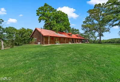 Spacious countryside home with a welcoming porch, surrounded by lush greenery and open skies.