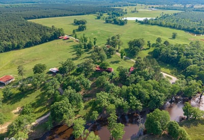 Expansive acreage with lush landscapes, multiple structures, and serene water features ideal for various outdoor endeavors.